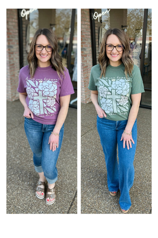 Woman wearing graphic tee with cross and floral design, styled with jeans in casual outfit.