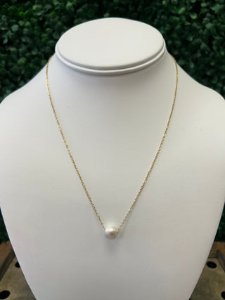 Delicate gold chain necklace with single white pearl pendant displayed on white jewelry bust stand