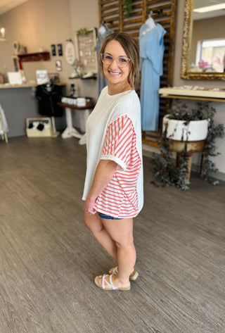 Woman wearing striped color-block top with white sleeves in casual retail boutique setting