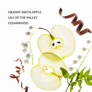 Granny Smith apple slices, lily of the valley flowers, and cedarwood bark ingredients flat lay.