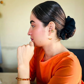 Woman wearing Alegria Accessories Ashton Earrings featuring gold hoop and ear cuff with beaded details.