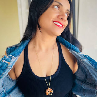 Woman wearing the Alegria Accessories Ashton Necklace, a gold chain with a round stone pendant.