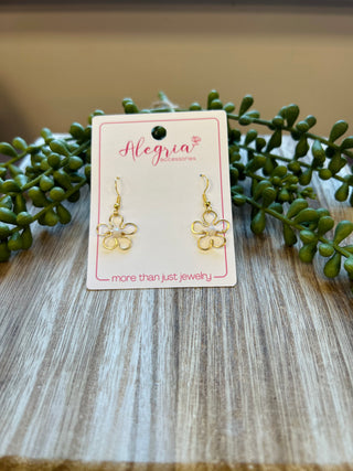 Gold flower-shaped dangle earrings displayed on Alegria Accessories card with green succulent plants on wooden surface.