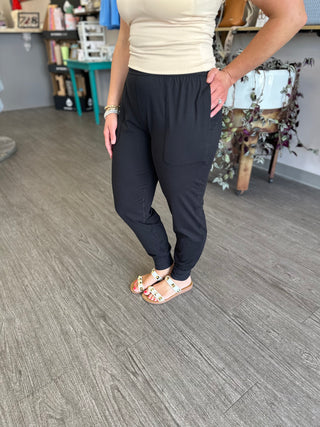 Woman wearing black jogger pants with elastic waistband and cuffed ankles in casual indoor setting.