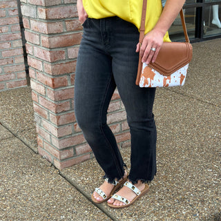 Woman wearing black high-rise slim straight jeans with yellow top and brown cowhide crossbody bag.