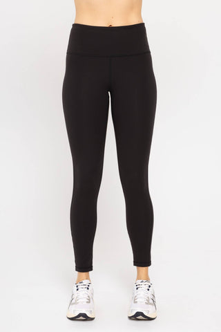 Black high-waisted tummy control leggings worn with white sneakers on neutral background