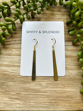 Gold-plated dangle earrings with textured finish displayed on branded card with greenery on wood background.