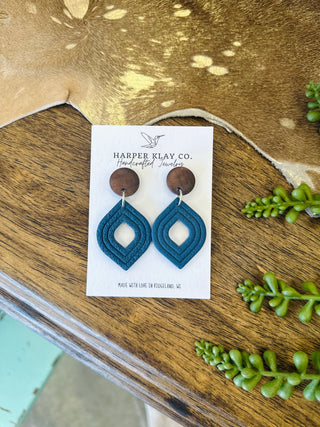 Handcrafted clay diamond-shaped dangle earrings with wood circle studs on display card.