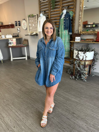 Woman wearing denim shirt dress standing in boutique store with clothing displays and mannequins