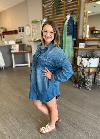 Woman wearing oversized denim shirt dress with pearl-studded sandals in boutique setting