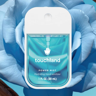 Touchland Power Mist hydrating hand sanitizer bottle surrounded by blue flower petals