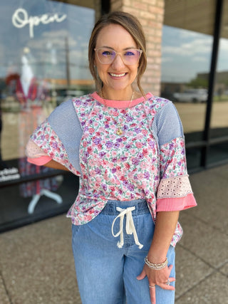 Woman wearing Haptics Blush Floral Fusion Top with mixed print panels and flutter sleeves outdoors.