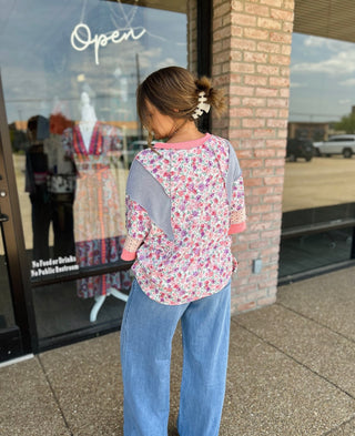 Woman wearing Haptics Blush Floral Fusion Top with mixed fabric panels and jeans, back view.