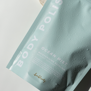 Bonblissity Body Polish Ocean Mist scrub package with water droplets on mint green surface