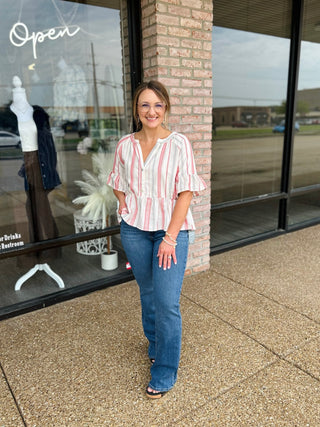 Woman wearing a VERY J boho striped ruffle-sleeve blouse paired with blue jeans outdoors.