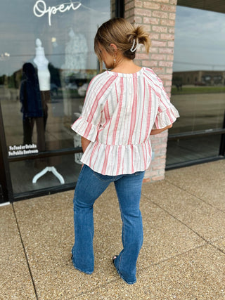 Woman wearing VERY J Boho Striped Blouse with ruffle sleeves and peplum hem, paired with flare jeans.