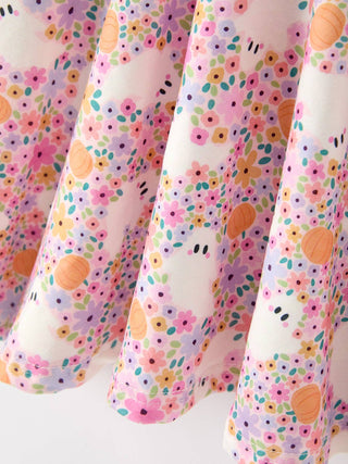 Close-up of a floral girls dress featuring ghost and pumpkin Halloween prints on flowing fabric.