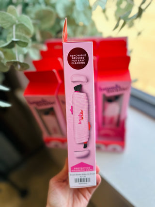 Hand holding pink Brush Bestie makeup brush in packaging with removable brushes feature highlighted