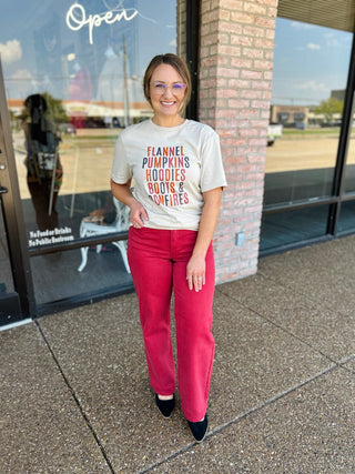 Woman wearing high-rise straight leg denim jeans paired with a graphic tee, standing outside a boutique.