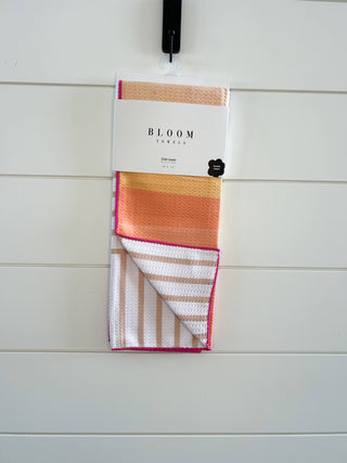 Bloom Towels striped kitchen dish towel in colorful sunset gradient pattern hanging on white wall