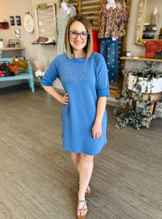 Woman wearing blue casual dress with short sleeves in boutique store setting