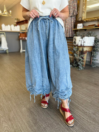 Woman wearing chambray wide leg pants with cinched drawstring hem and elastic waistband in casual setting.