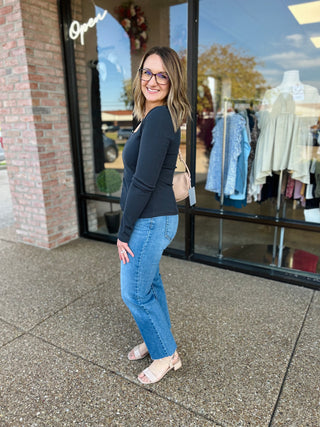 Woman wearing charcoal ribbed square neck top with jeans standing outside clothing store