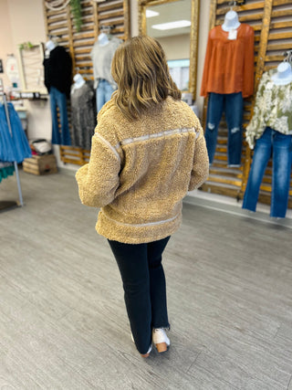 Woman wearing fuzzy textured pullover jacket while shopping in clothing boutique store