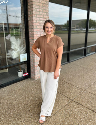 Woman wearing a casual short-sleeve V-neck blouse paired with wide-leg linen pants outdoors.