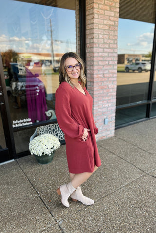 Woman wearing a long sleeve mini dress with balloon sleeves and pockets, styled with ankle boots.
