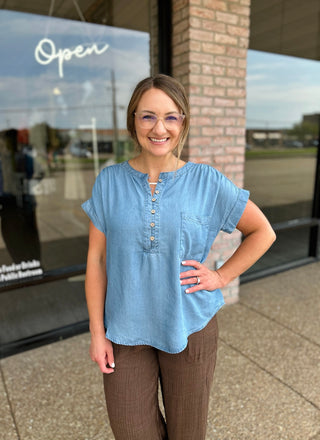 Woman smiling in a casual chambray henley blouse with button placket and chest pocket.