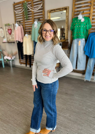 Woman wearing striped mock neck top with jeans in clothing store setting