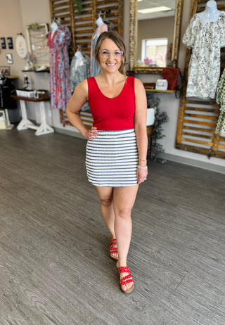Woman wearing red tank top and navy striped mini skort in clothing boutique store