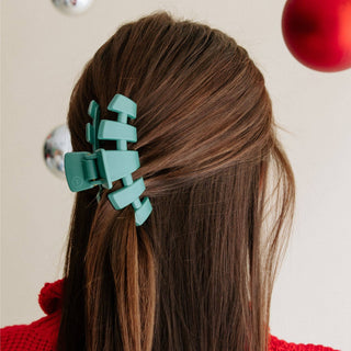 Woman wearing turquoise green classic hair clip in brown hair, shown from behind.