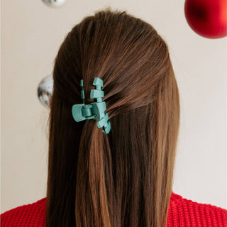 Person with brown hair wearing a turquoise TELETIES hair clip in a half-up hairstyle.