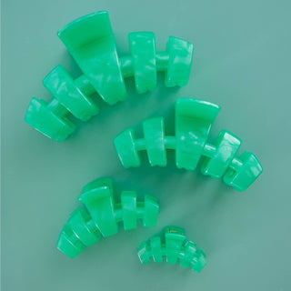 Green spiral hair ties arranged on a teal background showing coiled telephone cord design