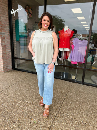 Woman wearing light wash cropped straight leg jeans with white top standing outside clothing boutique