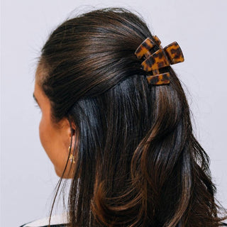 A woman wearing a tortoiseshell claw clip styled in a half-up hairstyle, viewed from behind.