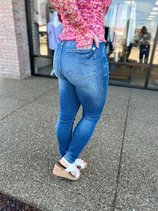Woman wearing classic tummy control skinny jeans with pink floral top and platform sandals.