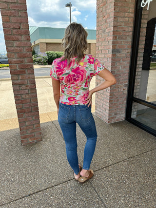 Woman wearing classic tummy control skinny jeans with floral top, standing outdoors showing back view of fit.