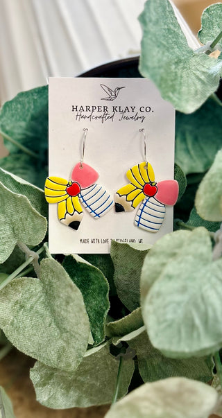 Colorful handcrafted polymer clay earrings with school-themed pencil and bow design on product card.