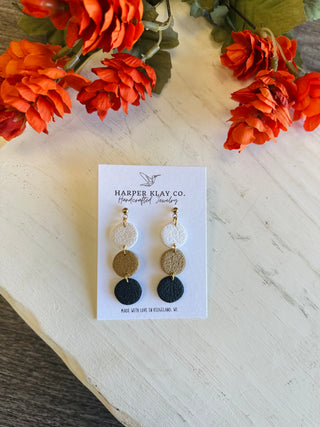 Handcrafted polymer clay triple circle drop earrings displayed on branded card with floral backdrop.