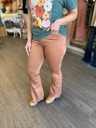 Woman wearing copper-colored stretch flare pants with floral t-shirt in retail store setting