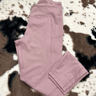Pink athletic leggings with pockets laid flat on cow print fur rug background