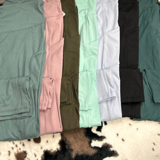 Stack of colorful athletic leggings with side pockets displayed on cowhide rug