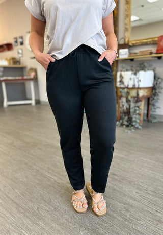 Woman wearing relaxed fit lounge pants with drawstring waist and pockets, paired with casual top and sandals.