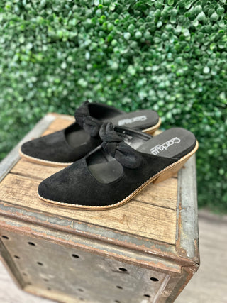 Corkys suede mule slides with knotted bow strap detail displayed on rustic wooden crate