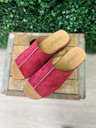Corkys suede slide sandals with open toe design and tan cushioned insole displayed on wooden crate