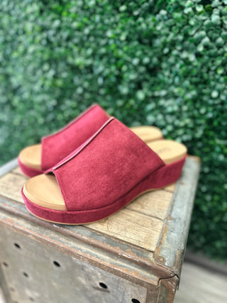 Corkys Take Notes suede slide sandals with wide strap and platform wedge sole displayed on rustic wood.