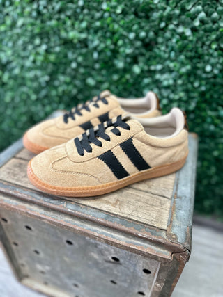 Corkys suede sneakers with black stripes and gum sole displayed on a rustic metal crate.